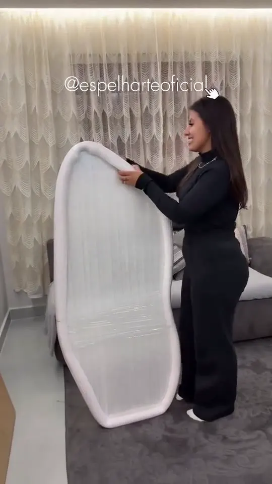 Cliente segurando o Espelho Lume embalado em espuma e filme plástico, antes de abrir